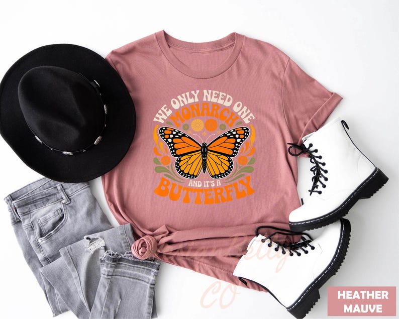 A pink t-shirt with a butterfly design, a black hat, a pair of white boots, and some jeans are arranged on a white background.