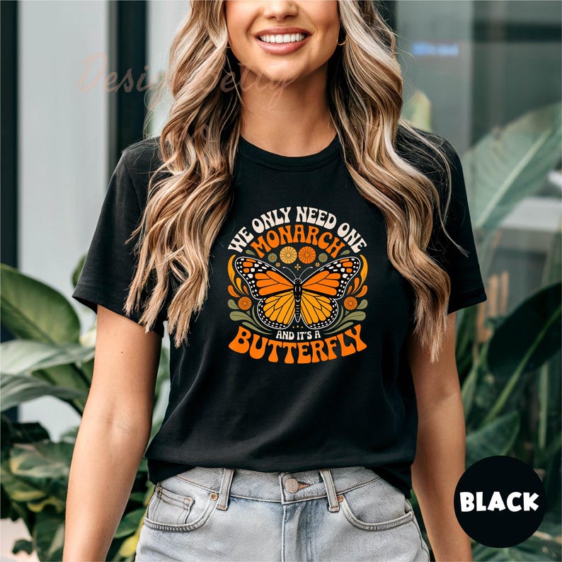 A woman wearing a black t-shirt with a graphic design of a butterfly and the text "We only need one monarch butterfly and it's a butterfly" printed on it.