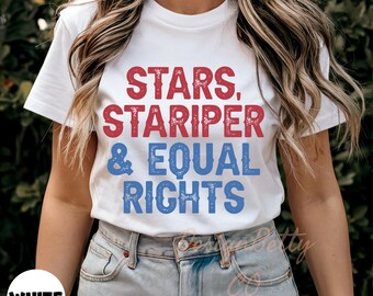 May include: White t-shirt with the text "STARS, STARIPER & EQUAL RIGHTS" in red and blue lettering. The shirt is a crew neck style and is being worn with blue jeans.