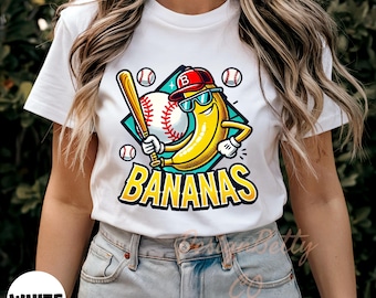 May include: White t-shirt featuring a cartoon banana wearing sunglasses and a baseball cap, holding a bat, with a baseball and the word "BANANAS". The design is set on a diamond shape with baseballs around it.