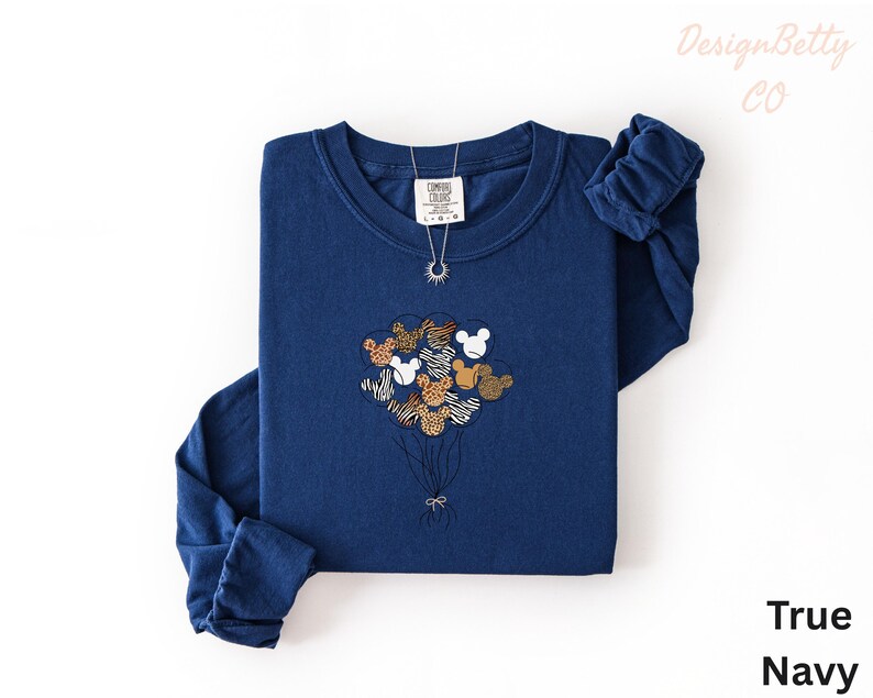 A navy blue long-sleeved shirt with a graphic of a bunch of balloons and a small elephant design on it, along with a necklace.