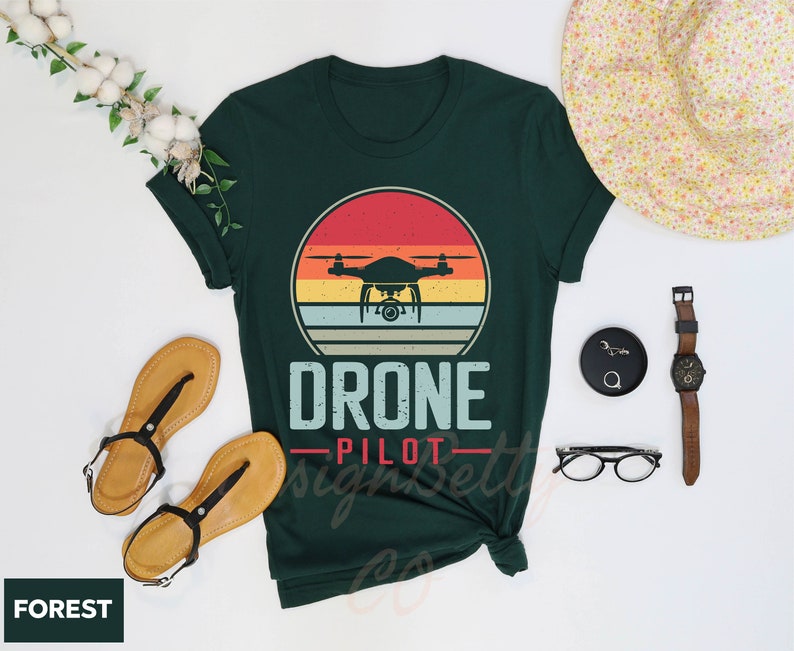 a shirt that says drone pilot next to a hat and sunglasses