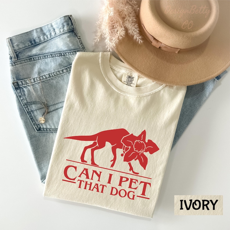 a casual outfit consisting of a white t-shirt with a red graphic, a pair of blue jeans, and a beige hat.