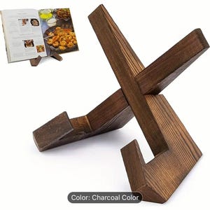 May include: Charcoal-colored wooden cookbook stand with an X-shaped design. The stand is holding a cookbook open to a recipe with images of food. The stand is made of wood and has a rustic appearance.