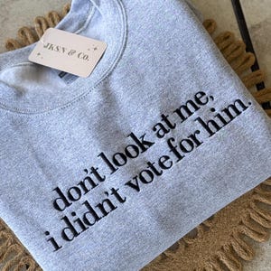 May include: Gray sweatshirt with the text "don't look at me, i didn't vote for him." embroidered in black.