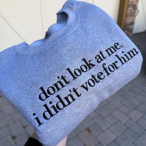May include: Gray sweatshirt with the text "don't look at me, i didn't vote for him" printed in black.