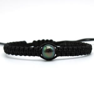 May include: Black macrame bracelet featuring a dark iridescent pearl. The bracelet is made of woven black cord, with the pearl centered in the design. The pearl has a dark green and black color.