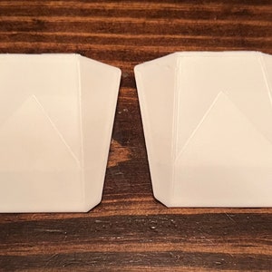 May include: Two white plastic pieces with a triangular shape and a textured surface.