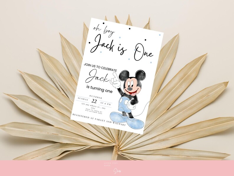 以下が含まれることがあります： 「oh boy Jack is One」のテキストとミッキーマウスの漫画の画像が描かれた白い招待状。 招待状には、日付と時間を含む1歳の誕生日のお祝いの詳細が含まれています。 カードは乾燥したヤシの葉を背景に設定されています。