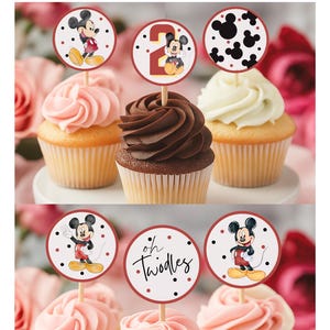 Può includere: Cupcake con decorazioni a tema Mickey Mouse e il numero 2. I cupcake hanno glassa rosa, cioccolato e bianca. Le decorazioni hanno un bordo rosso con pois neri.