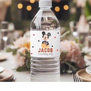 May include: A clear plastic water bottle with a white label featuring a cartoon Mickey Mouse illustration. The label includes the name "Jacob" and "2nd birthday party" in red and black text, with red and black polka dots.