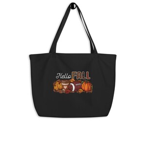 Könnte beinhalten: Schwarze Einkaufstasche mit einem grafischen Design aus einem Football, einer Kaffeetasse und einem Kürbis mit dem Text "Hello Fall" in braunen und orangen Buchstaben.