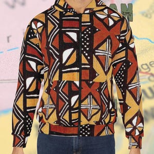 May include: A black, brown, and yellow patterned hoodie with a zipper closure. The hoodie has a geometric design with a hood.