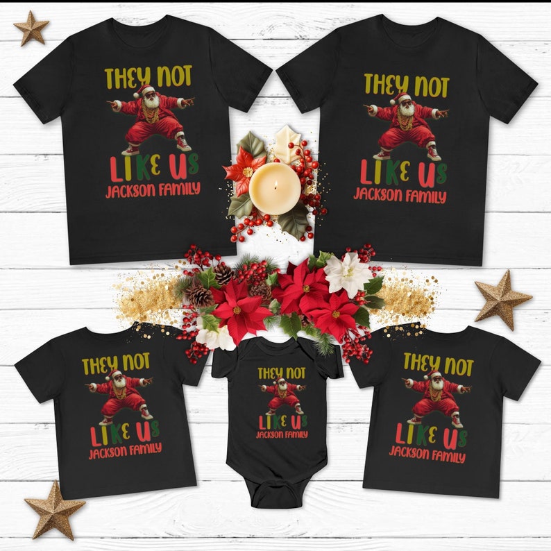 Puede incluir: Un conjunto de cuatro camisetas negras con un gr&aacute;fico de Pap&aacute; Noel rapeando. Las camisetas tienen el texto "They Not Like Us Jackson Family" impreso en ellas.