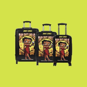 K&ouml;nnte beinhalten: Drei schwarze Koffer mit Rollen, die ein Cartoon-Bild von Betty Boop mit dem Text "They not like us Betty Boop" und dem Markennamen "Janet Jones" zeigen.