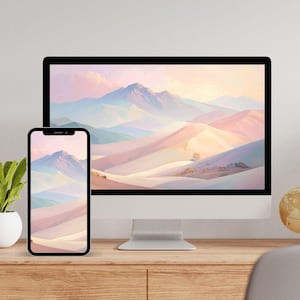 May include: A desktop computer monitor and a smartphone positioned side-by-side, both displaying a digital illustration of a mountain range with soft pastel pink, blue, and orange hues, set against a light-coloured wall on a wooden surface.