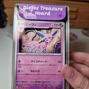 May include: A graded Pok&eacute;mon card featuring Espeon, with Japanese text and a purple and pink color scheme. The card is encased in a clear protective case with a purple label that reads "Diegos Treasure Hoard".