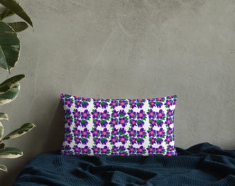 May include: A white pillow with a repeating pattern of purple flowers with green leaves. The pillow is on a dark blue bedspread.
