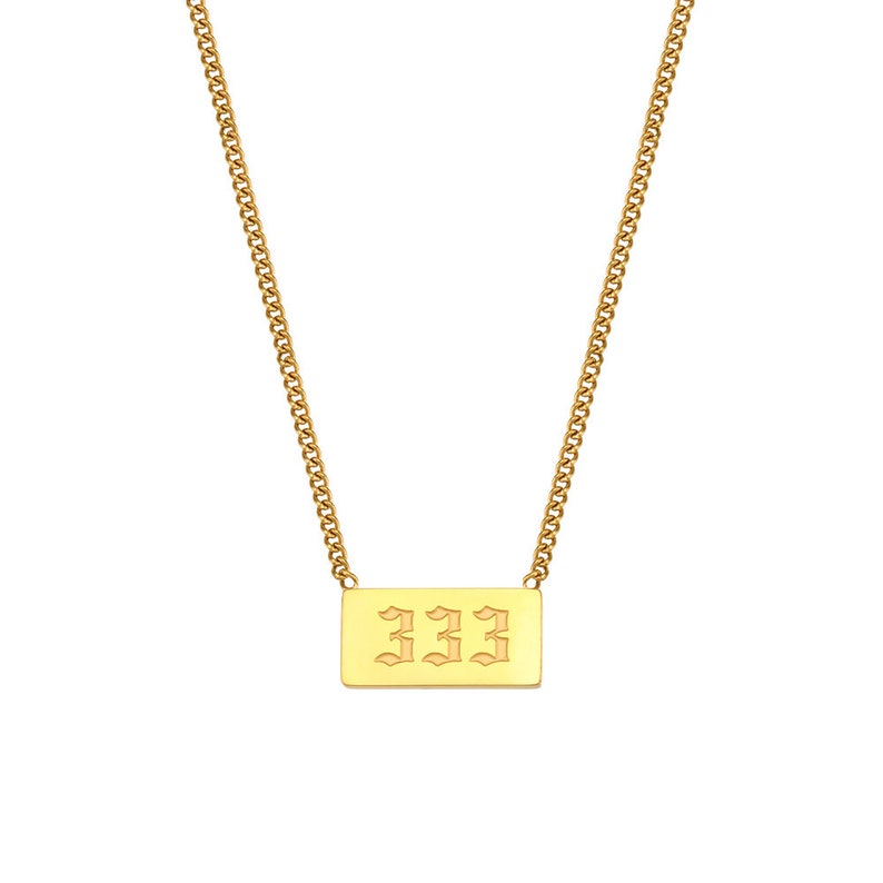 Puede incluir: Collar de cadena dorada con un colgante rectangular que presenta el n&uacute;mero 333 en una fuente g&oacute;tica.