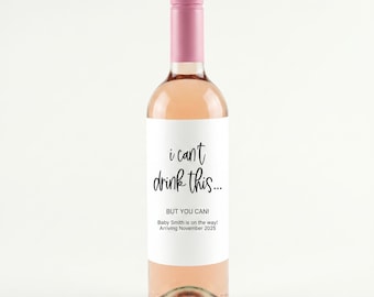 May include: A glass wine bottle filled with a light pink liquid, featuring a white label with black text that reads: I can't drink this... BUT YOU CAN! Baby Smith is on the way! Arriving November 2025. The bottle has a solid pink screw-top cap.