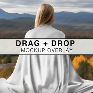 May include: A white fabric mockup overlay with the text "DRAG + DROP MOCKUP OVERLAY" on a white background. The overlay is draped over a person's back, with a view of a mountain range and trees in the background.