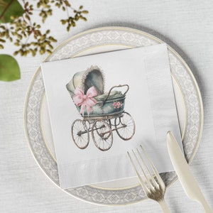 May include: A white paper napkin with a vintage baby carriage illustration. The carriage is green and white with a pink bow and flowers. The napkin has a decorative border.