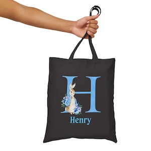 May include: Black tote bag with a blue letter H and a rabbit illustration. The name Henry is printed below the letter.