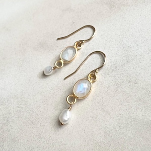 May include: A pair of gold earrings with a teardrop pearl and a moonstone oval. The earrings have a simple design and are perfect for everyday wear.
