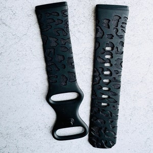 Pode incluir: Duas pulseiras de relógio pretas com um design de estampa de leopardo. Uma pulseira tem um fecho de fivela e a outra tem um fecho de pulseira de relógio padrão.