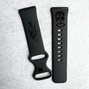 May include: Two black watch bands with different designs. One band has a graphic of a person with a hat and sunglasses. The other band has a graphic of a shield with a hand inside.
