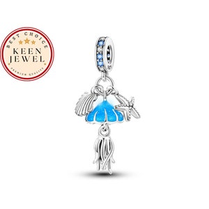 May include: Silver charm with a blue and white enamel jellyfish, a seashell, and a starfish. The charm has a small silver ring at the top for attaching to a bracelet or necklace.