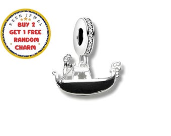 May include: A silver charm featuring a gondola with a gondolier. The gondola has a black base and is detailed with a person rowing. The charm has a loop with clear stones. The text "KEEN JEWEL BUY 2 GET 1 FREE RANDOM CHARM" is in a circle.
