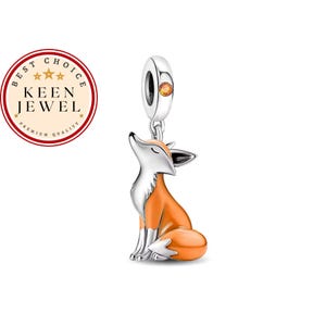 May include: A silver charm in the shape of a sitting fox with orange enamel accents on its back and tail. The fox has its head tilted upwards with closed eyes. The bail is a silver ring featuring a small, round, orange gemstone inlay.