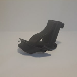 May include: A black plastic phone holder with a swivel design. The holder is designed to be mounted on a desk or table.