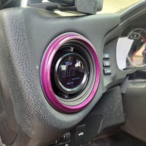 May include: A close-up of a car's dashboard featuring a purple-rimmed gauge displaying "8.88" volts. The gauge has a black face with white lettering and a warning indicator.