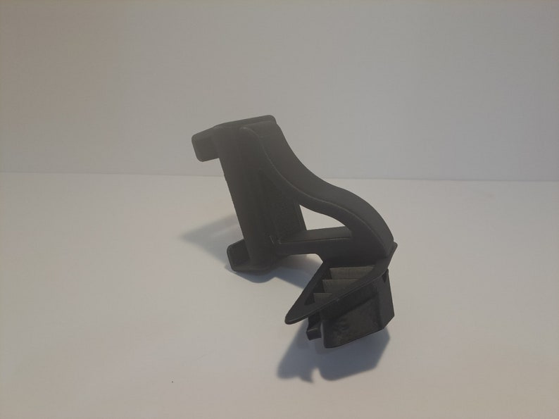 May include: A black plastic 3D printed object with a geometric design. The object has a curved shape and a flat base.