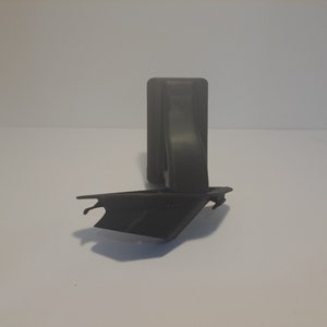 May include: A black plastic object with a rectangular base and a curved arm extending from the top. The object is designed to hold a phone or other device.