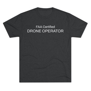 Peut inclure: Un t-shirt gris foncé chiné avec le texte "FAA Certified Drone Operator" imprimé en blanc.