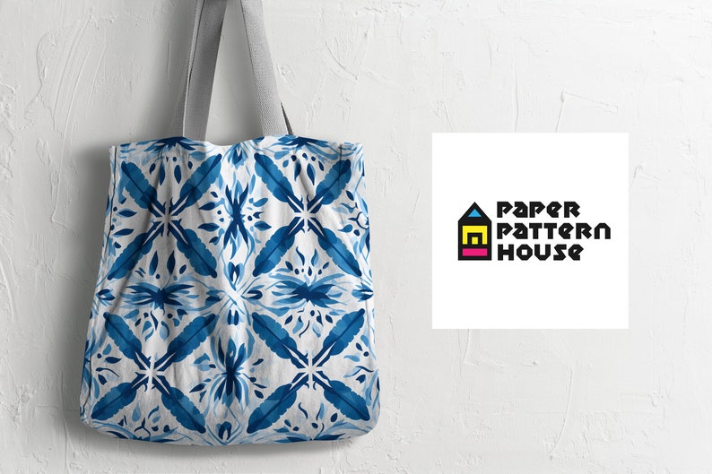 Op de afbeelding: Een witte tote bag met een blauw en wit patroon. De tas heeft een grijze handvat en de tekst "PAPER PATTERN HOUSE" is afgedrukt op een wit vierkant rechts van de tas.