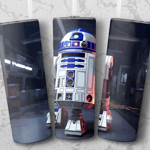 May include: A stainless steel tumbler featuring a detailed illustration of the Star Wars character R2-D2. The design showcases R2-D2's iconic blue, white, and red color scheme against a dark, industrial background. The tumbler is designed to hold approximately 20 ounces.