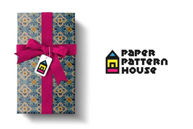 Op de afbeelding: Een cadeaudoos ingepakt in blauw, geel en bruin gepatroneerd papier met een roze lint en een label met de tekst "Paper Pattern House".