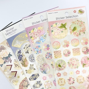 以下が含まれることがあります： 日本のテーマのステッカーシートのコレクション。各シートには、フラワーアレンジメント、鳥、伝統的なパターンなど、さまざまなデザインが施されています。「Sticker Selection」と「Made in Japan」の文字がパッケージに表示されています。