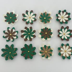 Peut inclure: Douze fleurs en papier faites à la main, disposées en grille. Les fleurs sont de couleurs vert, marron et crème, avec un centre doré. Idéal pour le bricolage ou la décoration.