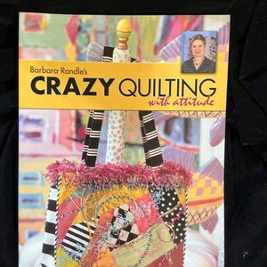 May include: A book cover titled "Crazy Quilting with Attitude" by Barbara Randle. The cover features a colorful, patchwork-style handbag with black and white striped handles and a pink fringe. A photo of the author is in the upper right corner.