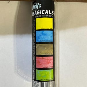 May include: A clear plastic tube containing Lindy's MAGICALS prairie wildflower pigment powders. The tube features a black label with color swatches in yellow, blue, brown, red, and green. Text includes product information and website address.