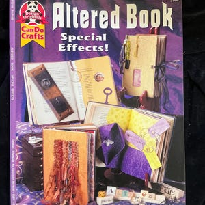 May include: The cover of an "Altered Book" craft book with the title in large, stylized letters. The cover features examples of altered book pages with keys, ribbons, and decorative elements. The book is titled "Altered Book Special Effects!" and includes the "Can Do Crafts" logo.