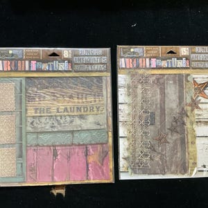 May include: Two packs of paper crafting supplies featuring vintage-inspired designs. The first pack has a light pink and brown color scheme with the text "The Laundry" and the second pack has a brown and white color scheme with a lace design and stars.