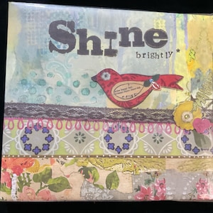 May include: A mixed media art piece with a collage of colorful patterns and textures. The piece features a red bird with the words "Shine brightly" in black lettering.