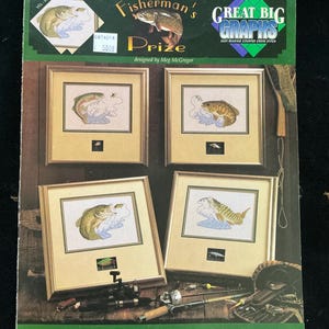May include: A cross-stitch pattern book titled "Fisherman's Prize" featuring four framed cross-stitch designs of freshwater fish. The cover includes text and images of fish, fishing gear, and the phrase "Great Big Graphs."