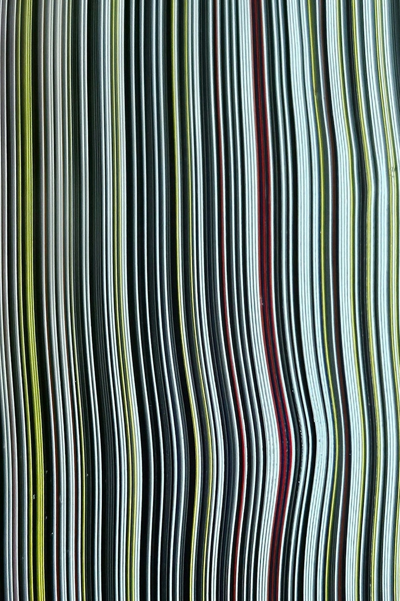 Op de afbeelding: Een close-up van een stapel kleurrijk, gestreept papier. Het papier is in een golvend patroon gerangschikt, waardoor een visueel interessante textuur ontstaat.